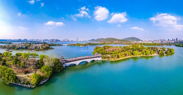 云龍湖是國(guó)家5A級(jí)景區(qū)，與西湖是姊妹湖，三面環(huán)山，一面臨城，宛若一顆明珠鑲嵌在徐州市中心。湛藍(lán)天空下，湖光瀲滟，綠木掩映，一湖碧水倒映著青山與城市遠(yuǎn)景，讓人流連忘返。圖為云龍湖泛月橋。孫博宇 攝_proc.jpg